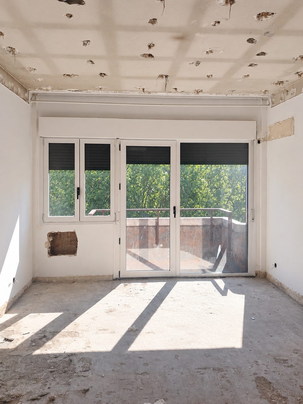 Ventana de dos hojas y puerta de balcón en PVC blanco con persianas, instaladas en una vivienda en obra